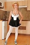 Lusty granny in maid uniform and stockings stripping in the kitchen
